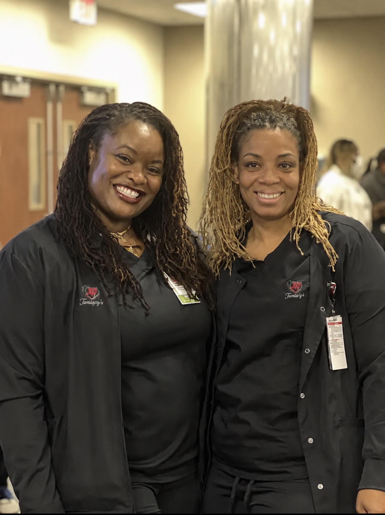 Two TamiaJoy's Nursing with Care professionals in branded black scrubs